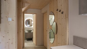 A bedroom with wooden paneling, a bed, and two mirrors on the wall.