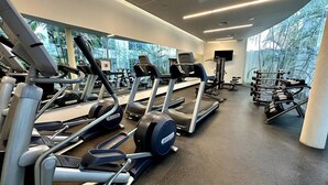 Une salle de sport équipée de tapis de course, de vélos elliptiques et d’appareils de musculation.
