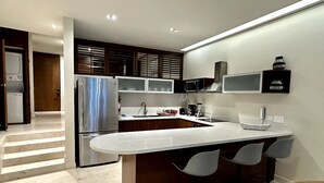 Une cuisine moderne dotée d’un grand îlot central, d’appareils électroménagers en acier inoxydable et de tabourets de bar.