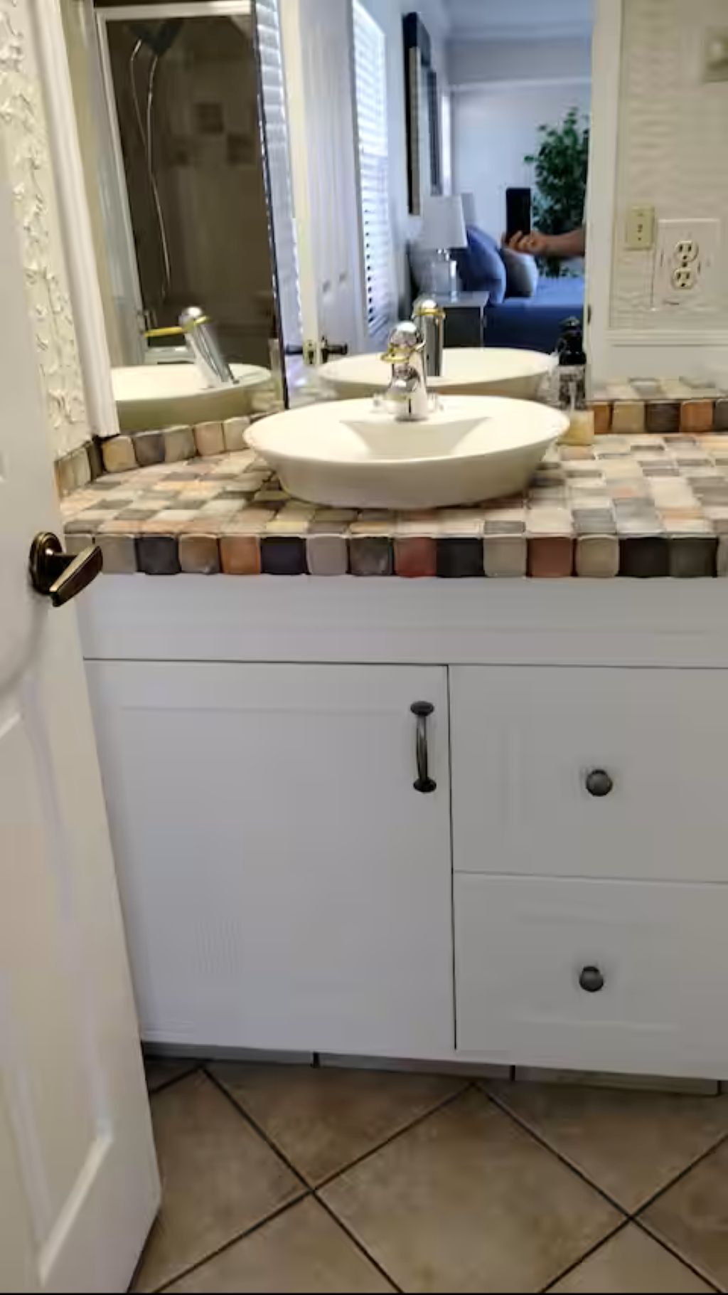 Une salle de bain avec un lavabo blanc, un miroir et un sol carrelé.