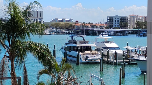 A marina with several boats docked, surrounded by buildings and palm trees.