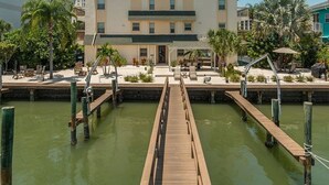 A hotel with a central courtyard, a wooden dock leading to a pool, and a view of the surrounding buildings.