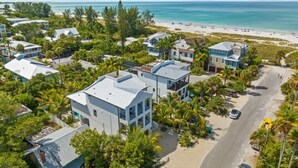 A coastal residential area with modern houses, a beach, and a clear view of the ocean. - NEW! Meet Me At Sunset! 3 Homes from the Beach! (Anna Maria)
