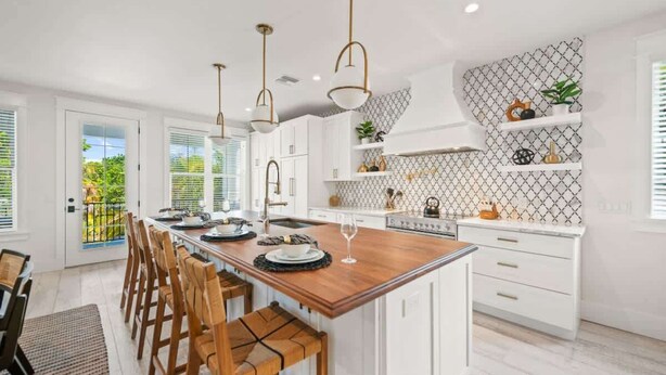 A modern kitchen with white cabinetry, a wooden island, pendant lighting, and a patterned backsplash. - NEW! Meet Me At Sunset! 3 Homes from the Beach! (Anna Maria)