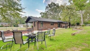 A brick building with a covered patio area, outdoor seating, and a fire pit.