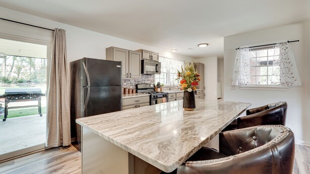 A modern kitchen with a marble countertop, stainless steel appliances, and a dining area with leather chairs. - Group Getaway w/ Fenced Yard & Pool Table in Wrens (Wrens)
