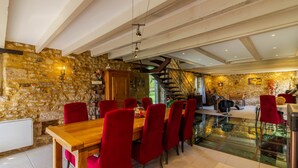 Een eetgedeelte met een stenen muur, een houten tafel en rode stoelen.