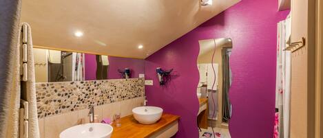 Une salle de bain avec deux lavabos, un miroir et un mur recouvert de carreaux.