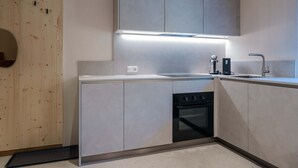 A modern kitchen with grey cabinets, a built-in oven, and a stainless steel sink. - Starry Loft 212 (Novale di Sotto)