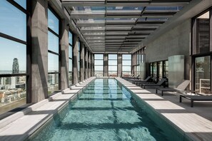 A modern indoor swimming pool with clear glass walls and a city view. - Top Rentals Huergo (Buenos Aires)