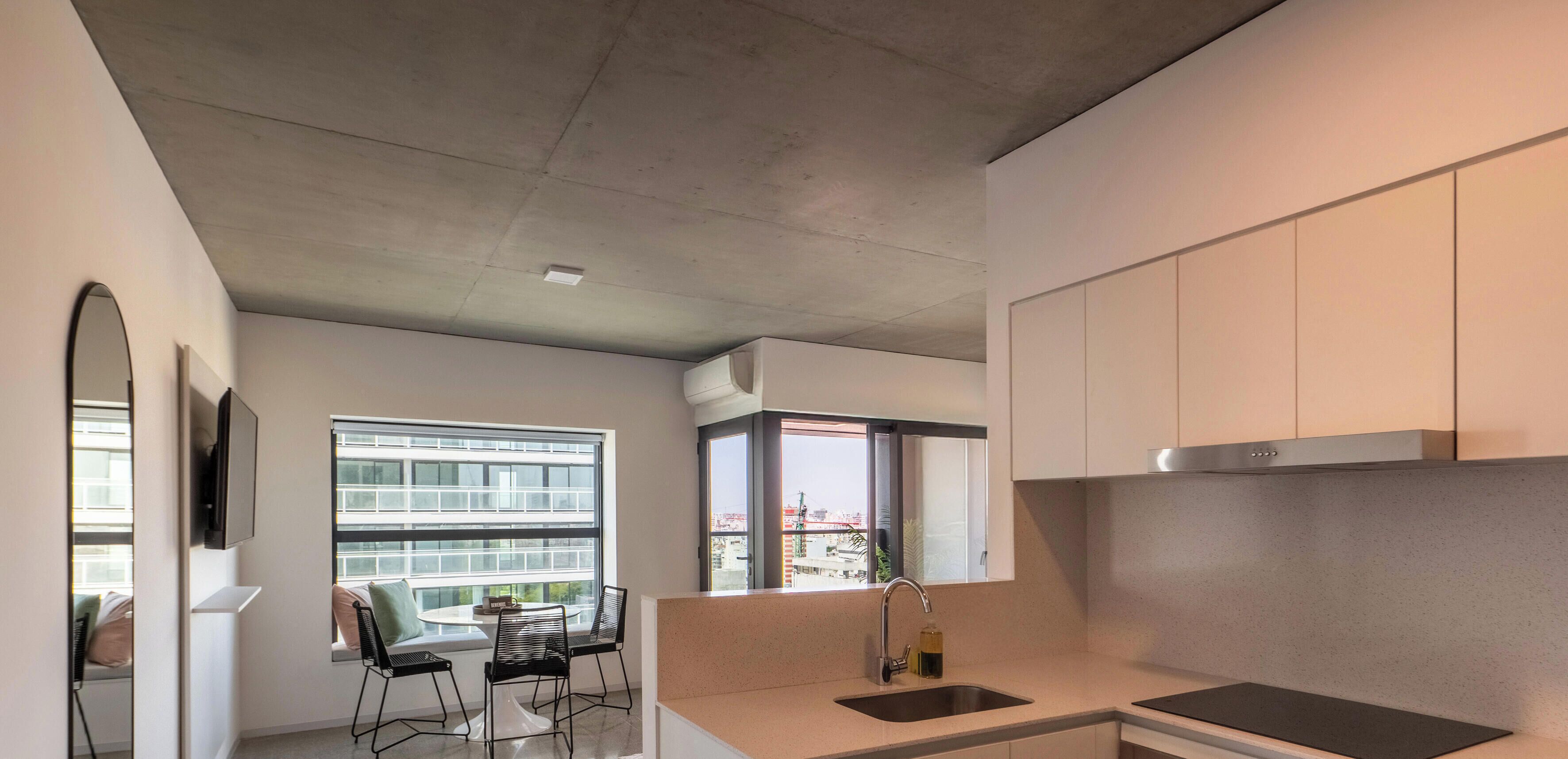 Una cocina moderna con estufa integrada, un lavamanos y ventana con vista a la ciudad.
