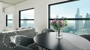 A modern office space with large windows, a round table, and a vase of flowers. - Top Rentals Huergo (Buenos Aires)