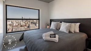 A modern hotel room with a large window, a neatly made bed, and a city view. - Top Rentals Huergo (Buenos Aires)