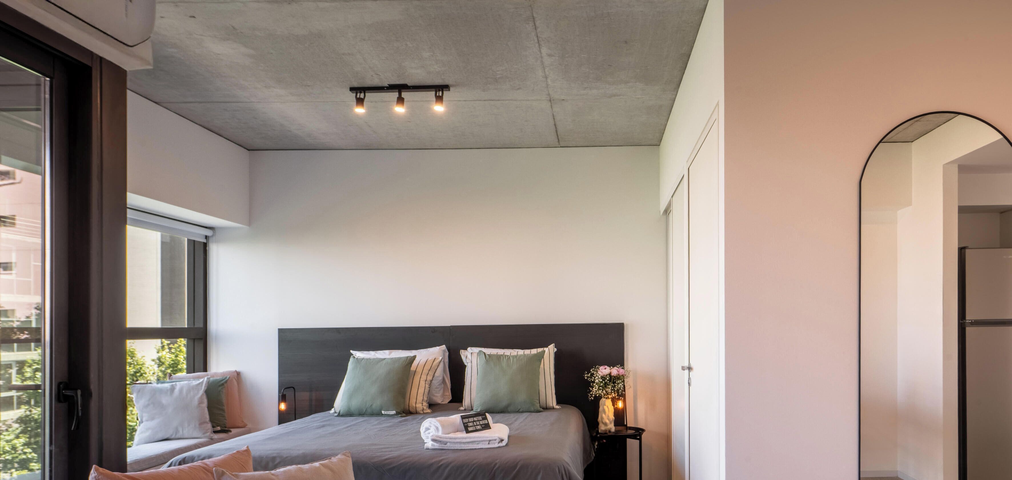 Um quarto moderno com uma cama grande, uma mesinha de cabeceira e uma luminária.
