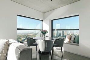 A modern room with a dining table, grey chairs, a sofa with cushions, and large windows offering a city view. - Top Rentals Huergo (Buenos Aires)