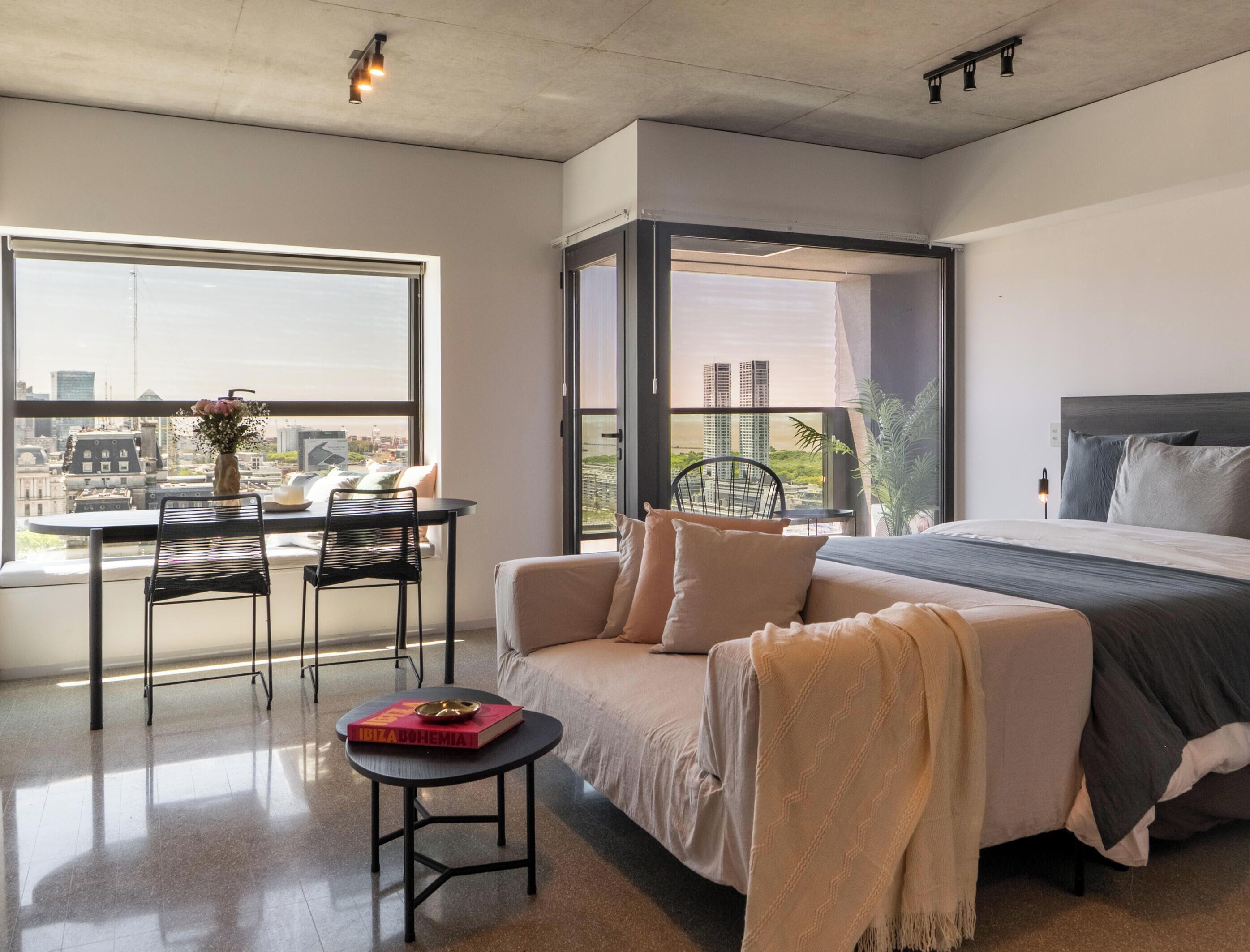A modern bedroom with a bed, a sofa, a table, and a chair.
