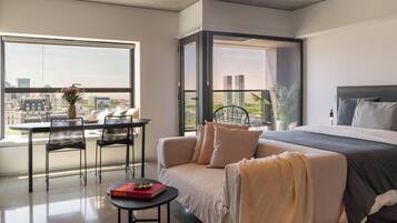 Un dormitorio moderno con cama, sofá, mesa y silla.