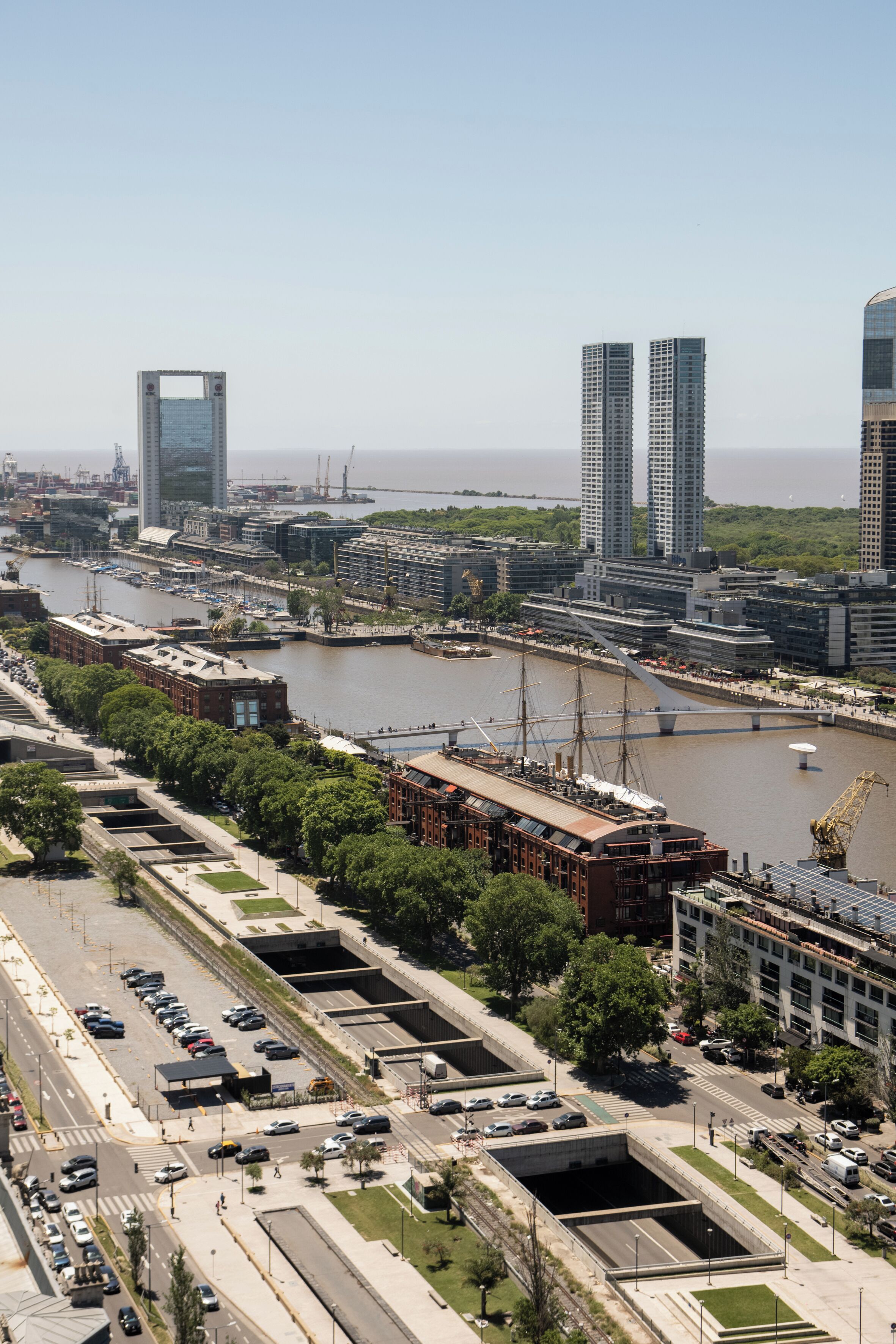 Un paisaje urbano con un río, edificios modernos y un puente.