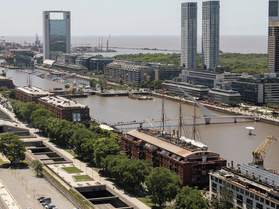 Un paisaje urbano con un río, edificios modernos y un puente.