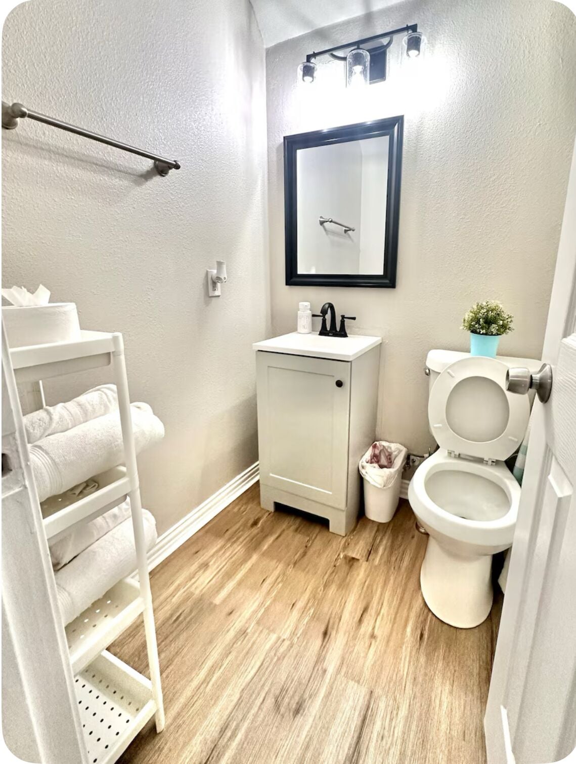 A compact bathroom with a white sink, a toilet, and a towel rack with towels.