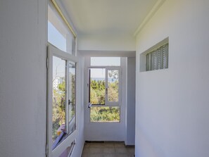 A narrow hallway with a door leading to a balcony with a view of trees and a building. - Cubo's Estudio Reme Calypso II / air conditioning / terrace / sea views (Mijas Costa)