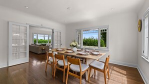 Un vaste espace dédié à la salle à manger, avec une table en bois dressée pour six personnes, entourée de chaises.