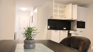 A modern kitchen with white cabinets, a black countertop, and a built-in microwave. - Comfort Apartments Villach Self CheckIn (Villach)