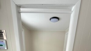 A compact room with a foldable bed, a ceiling light, and a wall-mounted control panel. - Steps to Metra - Fully Updated - Downtown Harvard (Harvard)