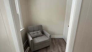 A room with a grey sofa, a wooden floor, a white door, and a ceiling light fixture. - Steps to Metra - Fully Updated - Downtown Harvard (Harvard)