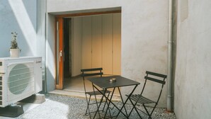 A small outdoor seating area with a table and chairs, a potted plant, and an air conditioning unit. - 2 bedrooms triplex in historic heart of Liege (Liège)