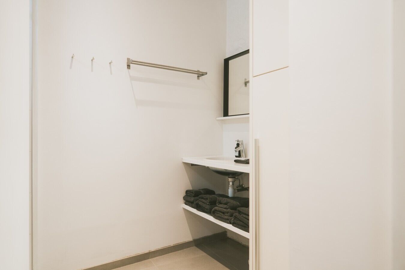 Une petite salle de bain fermée, avec un lavabo blanc, un miroir et un porte-serviettes.