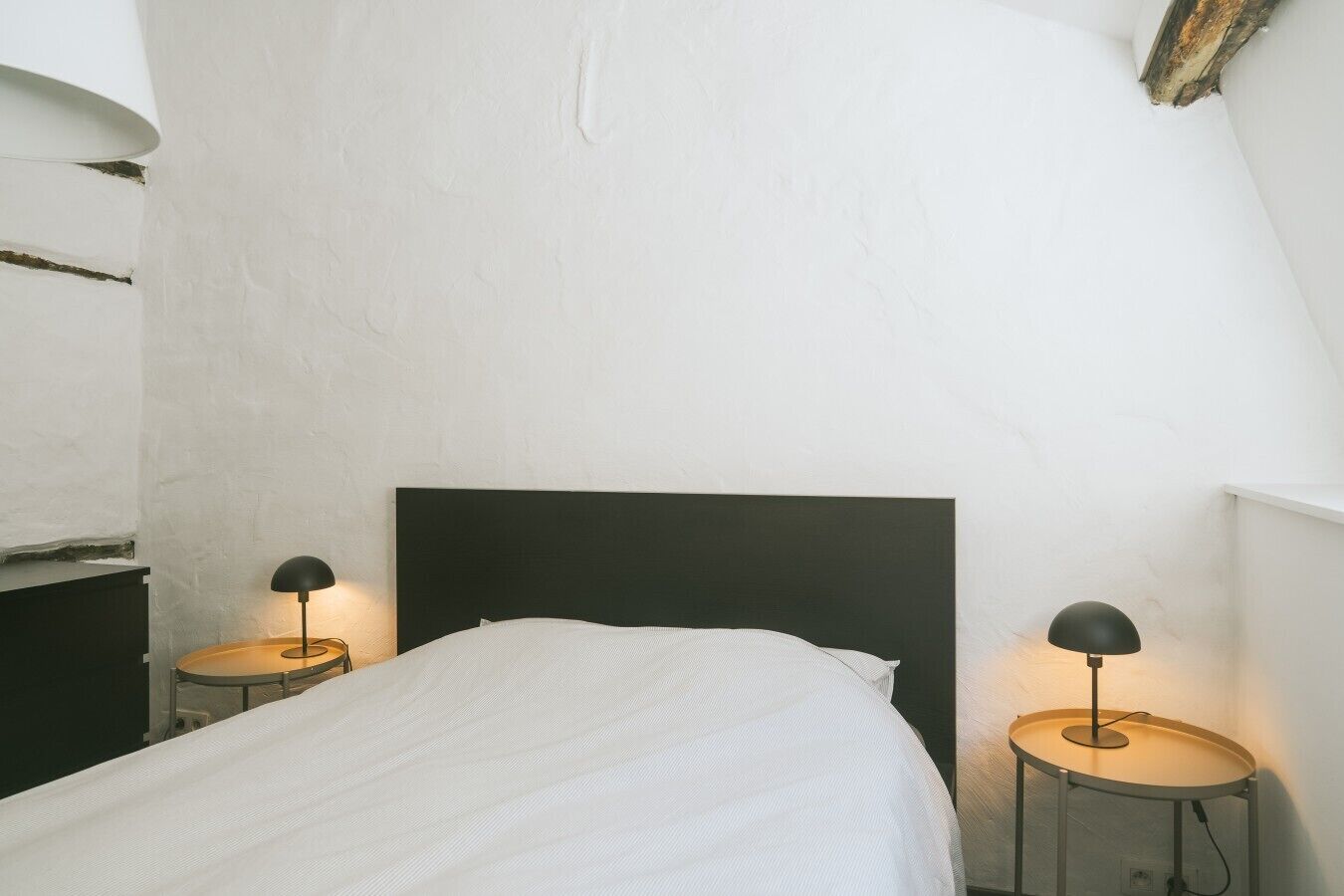 A bedroom with a single bed, two bedside tables, and a black headboard.