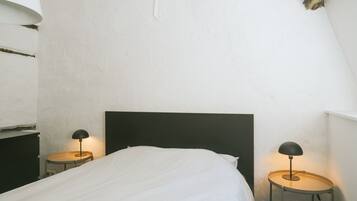 A bedroom with a single bed, two bedside tables, and a black headboard.