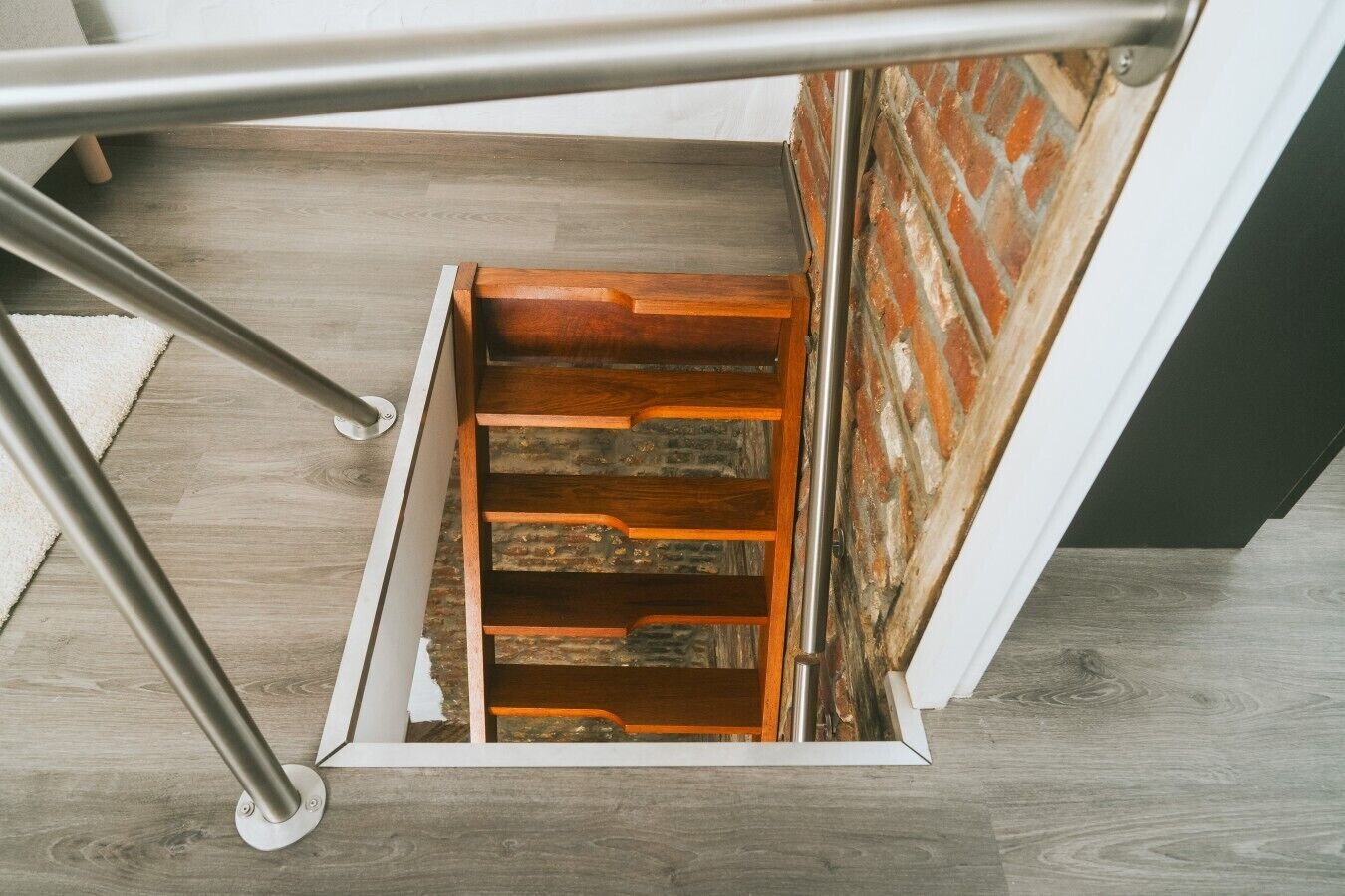 Un escalier en bois avec des rampes en métal, menant à un niveau inférieur.
