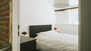 A bedroom with a bed, a nightstand, a lamp, and a window. - 2 bedrooms triplex in historic heart of Liege (Liège)
