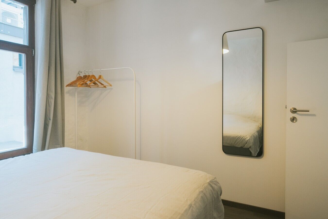 Una habitación de hotel con cama, armario, espejo y puerta.