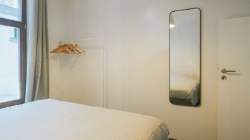 Una habitación de hotel con cama, armario, espejo y puerta.