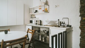 A compact kitchen with white cabinetry, a round dining table, and a brick wall. - 2 bedrooms triplex in historic heart of Liege (Liège)