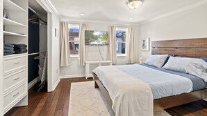 A bedroom with a bed, a wardrobe, a radiator, and a window with curtains. - The Bella Vista Townhouse (Philadelphia)