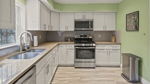 A modern kitchen with white cabinets, stainless steel appliances, and a herringbone wood floor. - The Bella Vista Townhouse (Philadelphia)