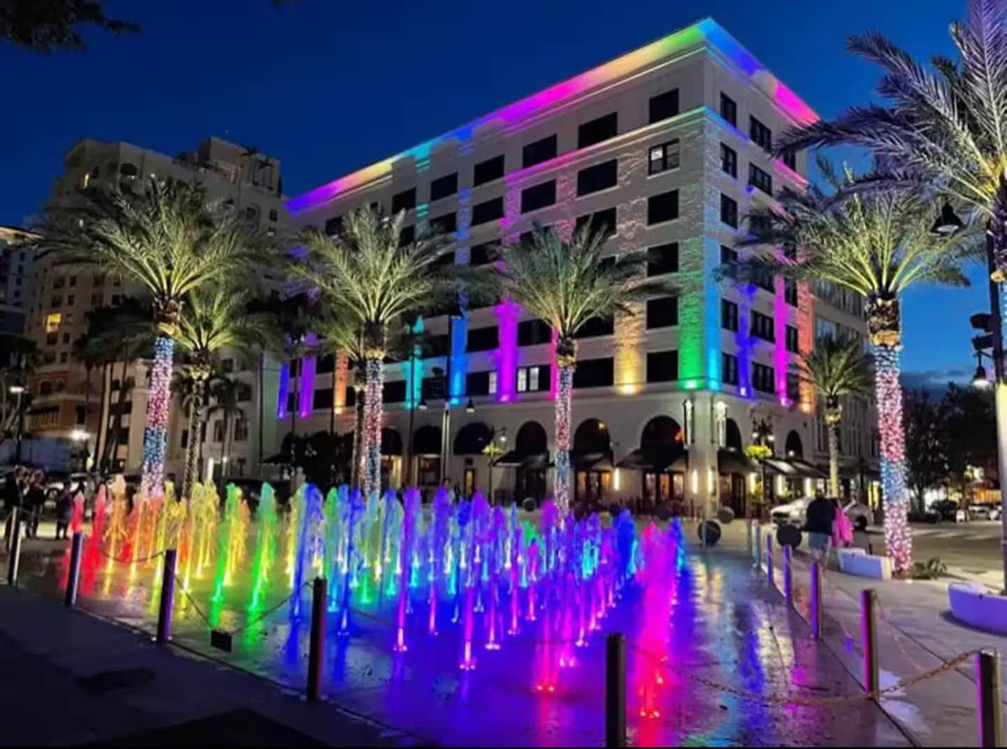 A brightly lit building with a fountain in front.