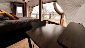 Eine Zeltoase mit Bett, Tisch und Blick ins Freie.