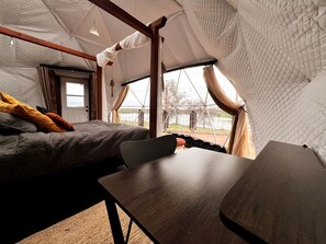 A tented accommodation with a bed, a table, and a view of the outdoors. - Luxurious Rustic Dome with Private Deck and Picnic Table in California (Grass Valley)