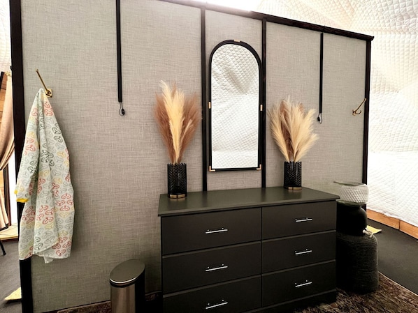 A room with a black dresser, a mirror, and pampas grass in vases.