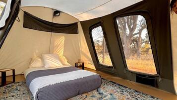 Una carpa con cama, ventana y una alfombra estampada.