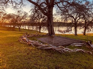 A swing set under a large tree in a grassy area with a lake in the background. - Cute, Lakeside Glamping Bell Tent #2, Wheatland, California (Grass Valley)