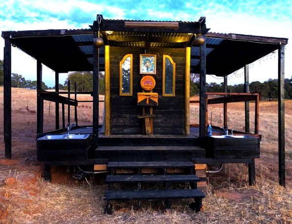 A rustic wooden structure with a bench, a small table, and a decorative element in the center.