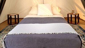 A tent with a bed, pillows, a blanket, and two nightstands. - Cute, Lakeside Glamping Bell Tent #2, Wheatland, California (Grass Valley)