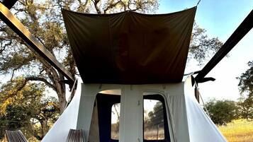 A tent with a canopy, a bench, and a wooden deck.