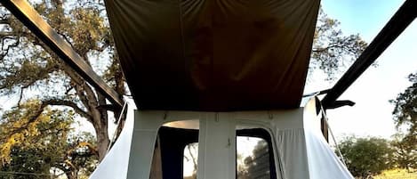 A tent with a canopy, a bench, and a wooden deck.